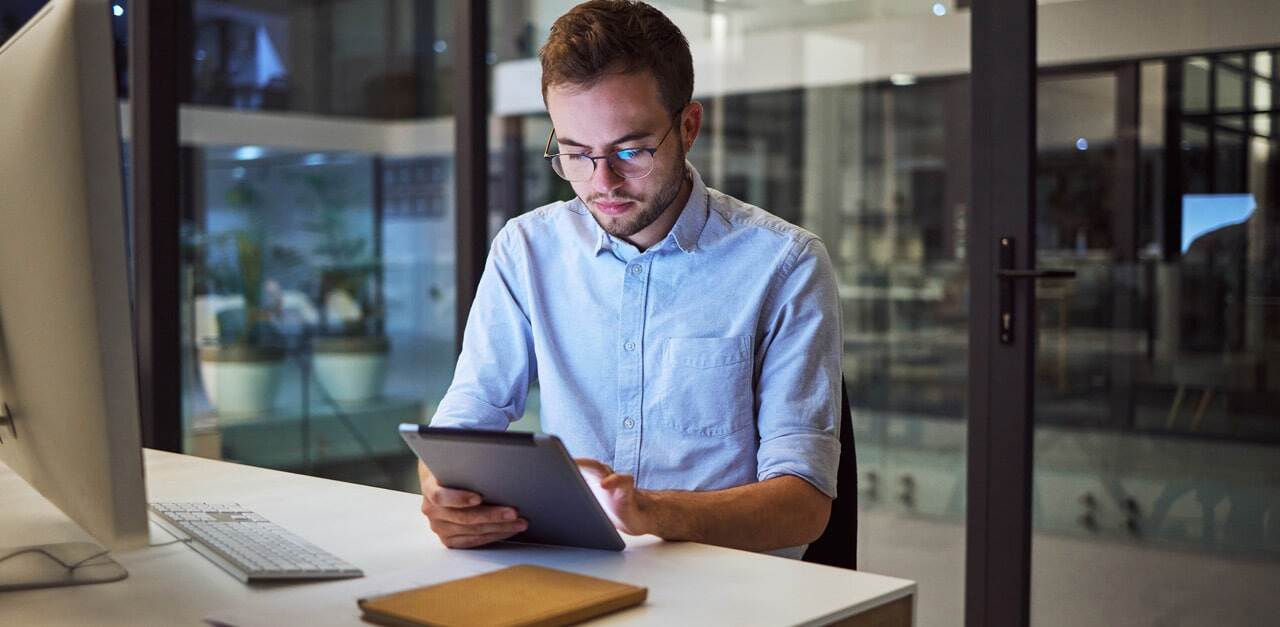 Business-communication-and-overtime-man-with-tablet-and-computer-at-desk-min.jpg