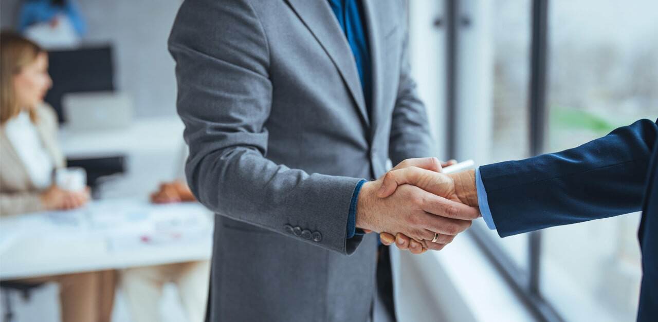 Close-up-of-two-business-people-shaking-hands-while-sitting-at-the-working-place-min.jpg